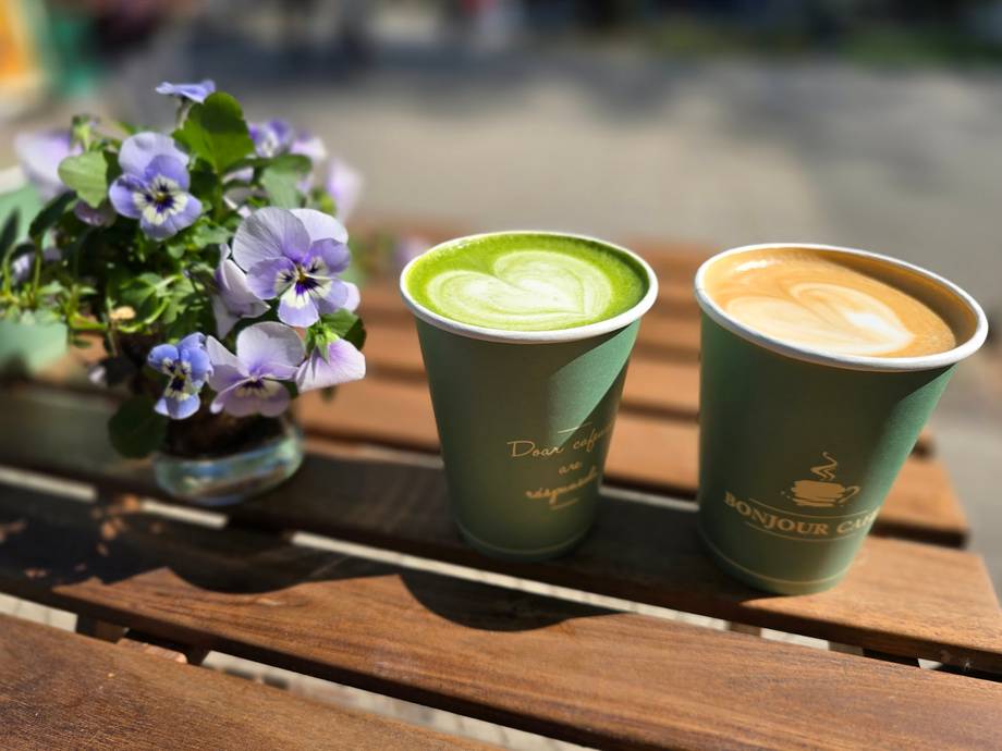 Matcha latte and cappuccino with fresh flowers on wooden table