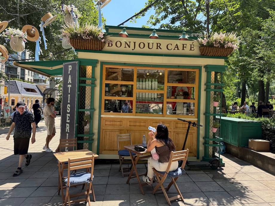 Bonjour Cafe storefront with wooden kiosk, outdoor seating, and park setting in Moldova