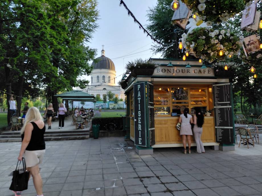 Street kiosk vendor with monastery cathedral dome in background, Chișinău