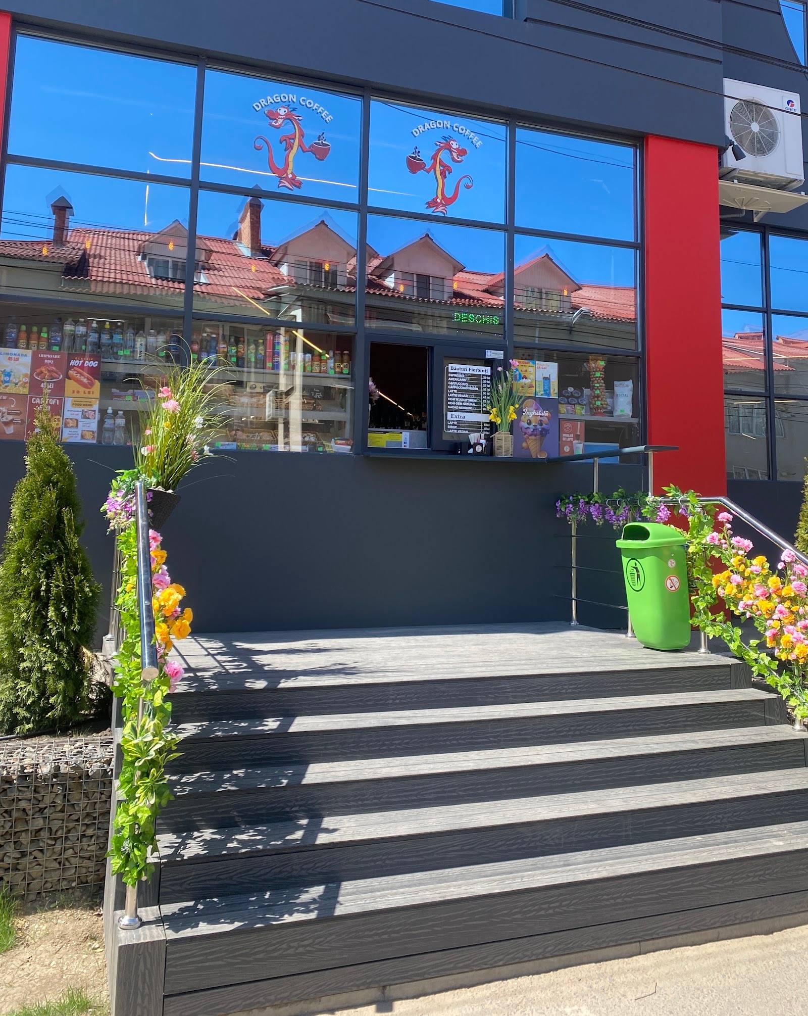 Modern storefront with red facade, large windows, and welcoming entrance decorated with flowers