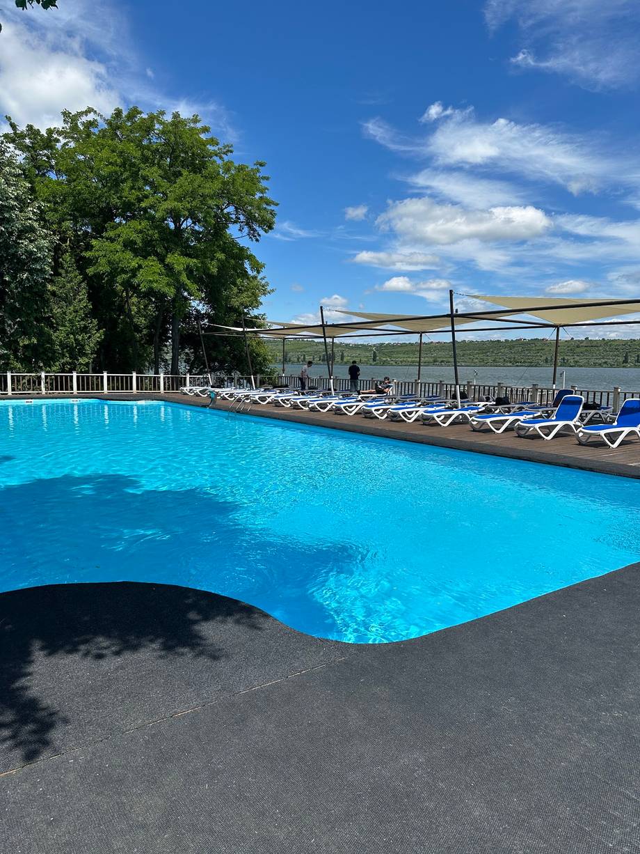 Resort pool with loungers and scenic hillside views, clear summer day