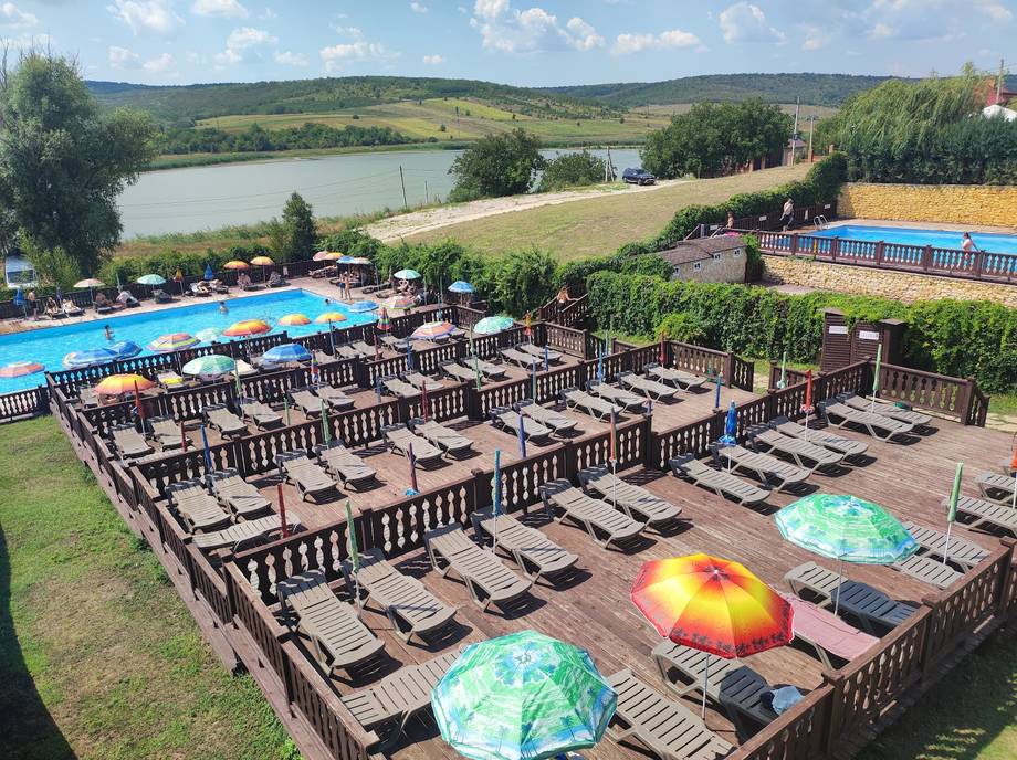 Aerial view of waterfront resort with lounging areas, pools, and river landscape