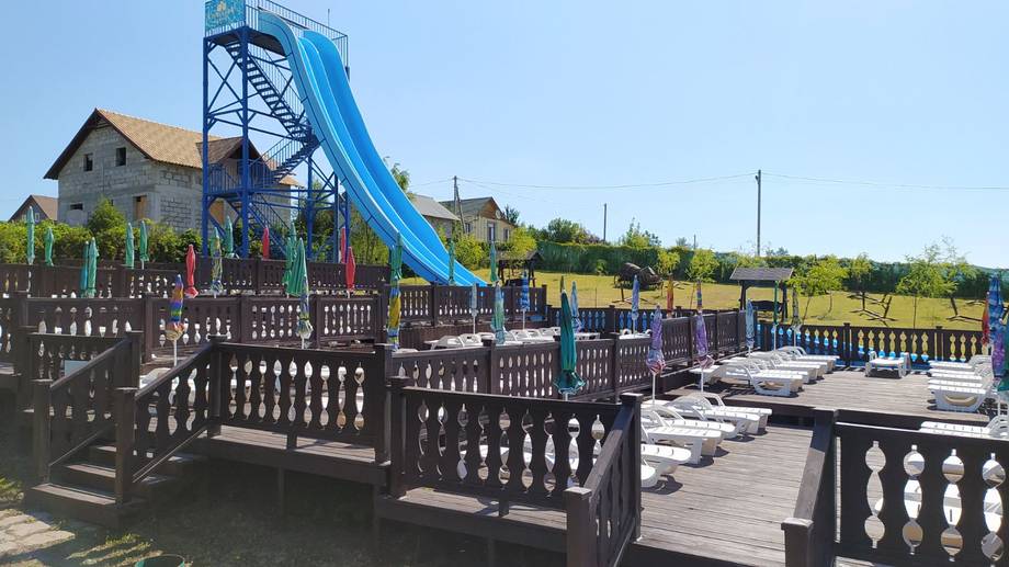 Water park with large blue slide and wooden play structures under clear sky