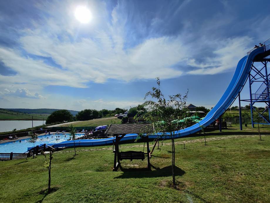 Water park with blue slide and trampoline on manicured lawn overlooking lake