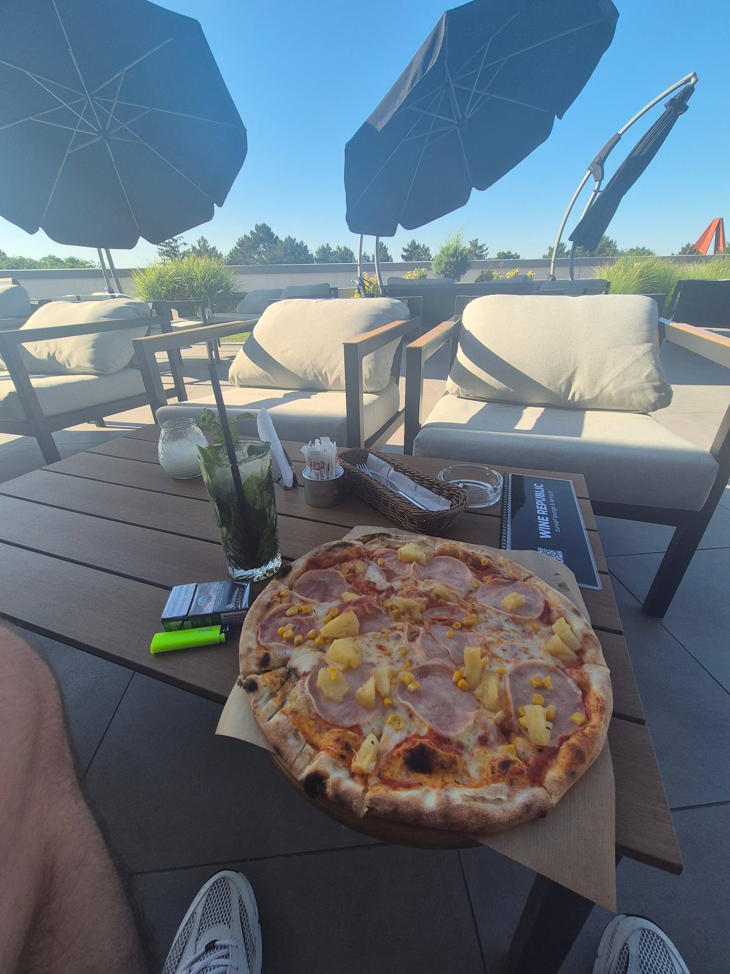 Pizza served on sunny terrace with umbrellas and countryside views