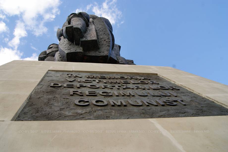 Soviet monument with sculptural figure and dedication plaque against blue sky