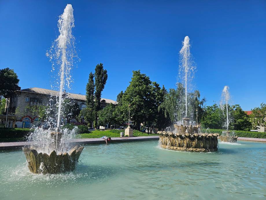 Public garden with illuminated fountains and landscaped grounds under clear blue sky
