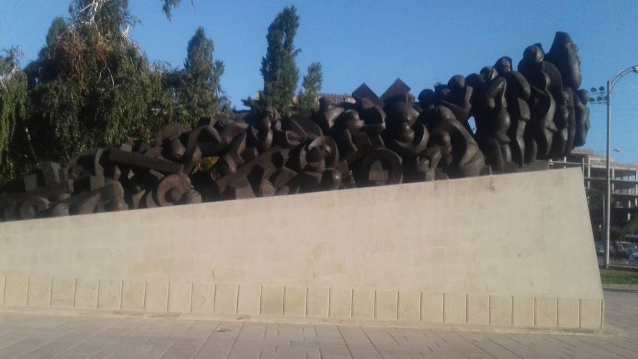 Bronze sculpture installation with stylized figures on pale concrete base
