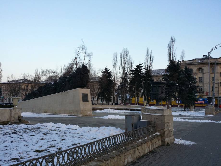 Winter urban plaza with snow, trees, and institutional buildings