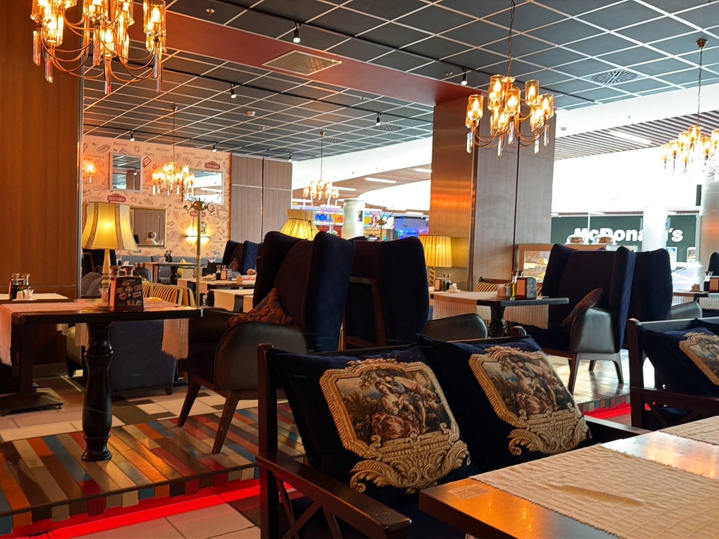 Modern hotel or event space lobby with black seating, decorative pillows, and contemporary chandeliers