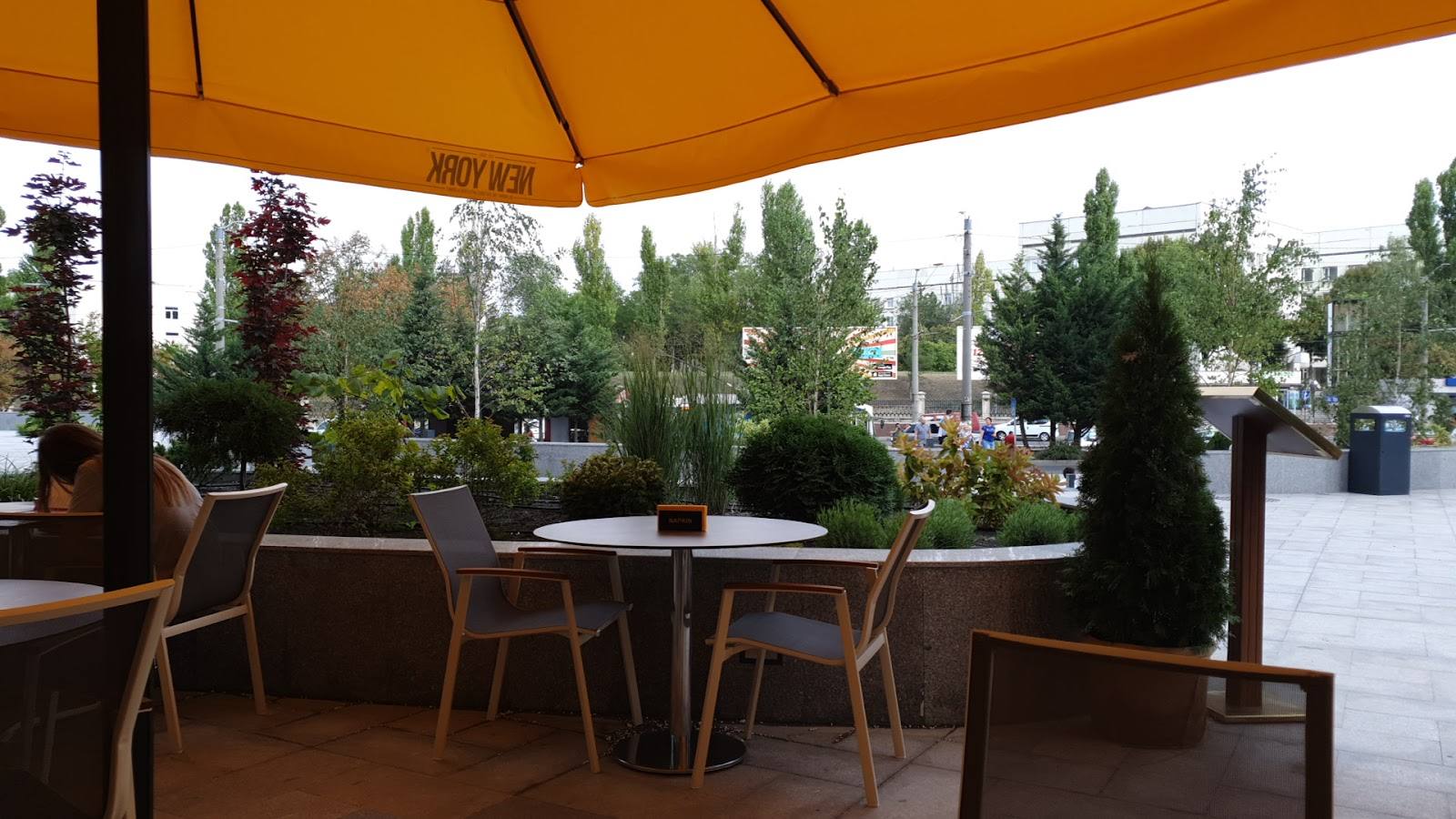 Outdoor terrace with orange sun shade, wooden seating, and garden views