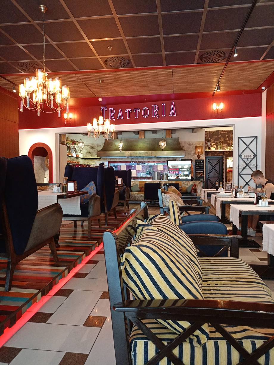 Trattoria restaurant interior with bold red signage, modern furnishings, and open kitchen