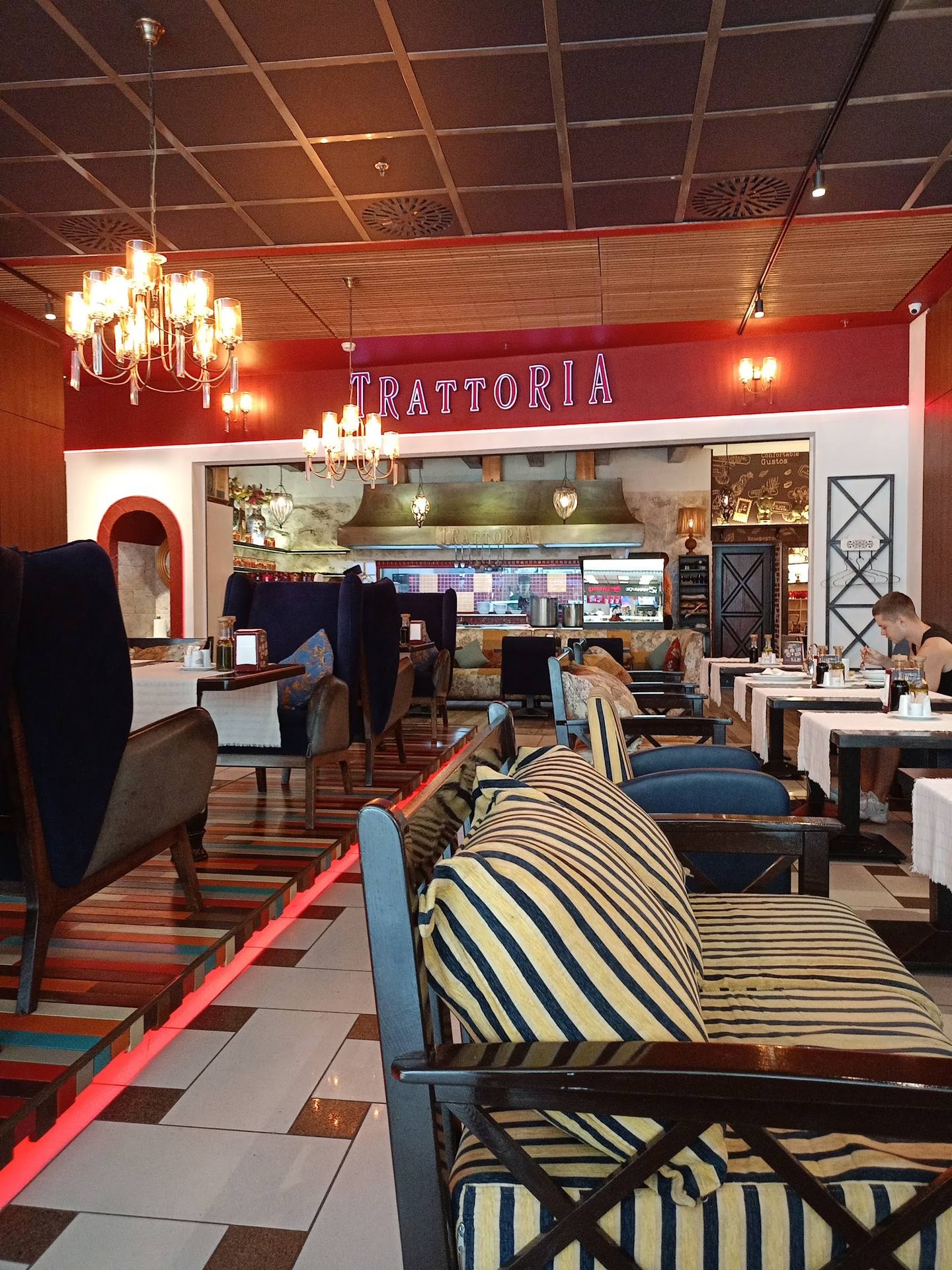 Trattoria restaurant interior with bold red signage, modern furnishings, and open kitchen