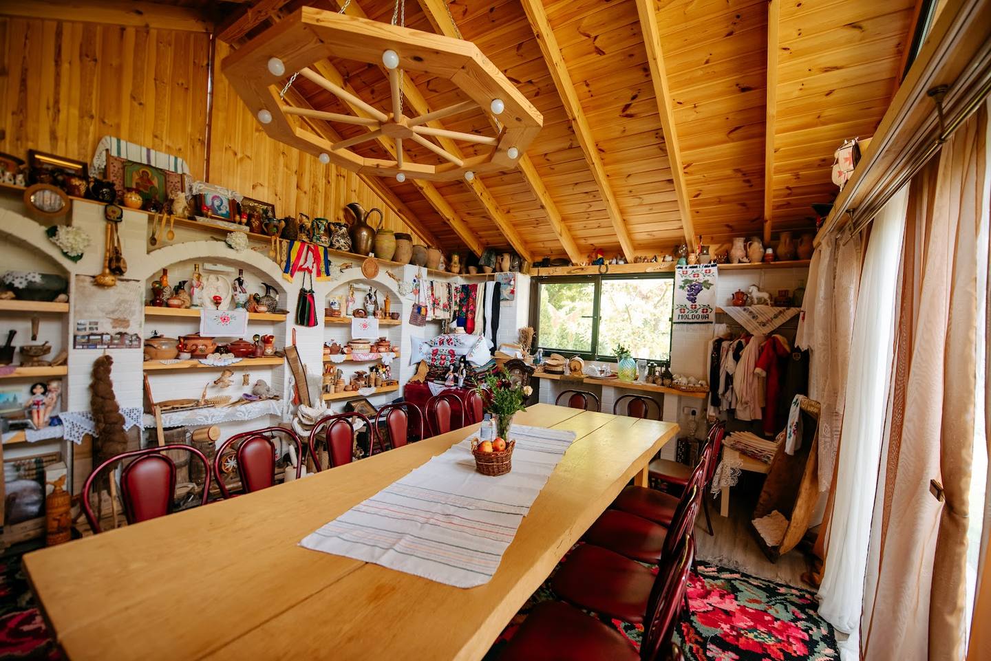 Rustic wooden interior with exposed beam ceiling, long communal table, and wine display shelves