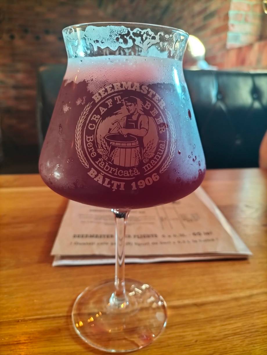 Purple craft beer in branded glass on wooden table