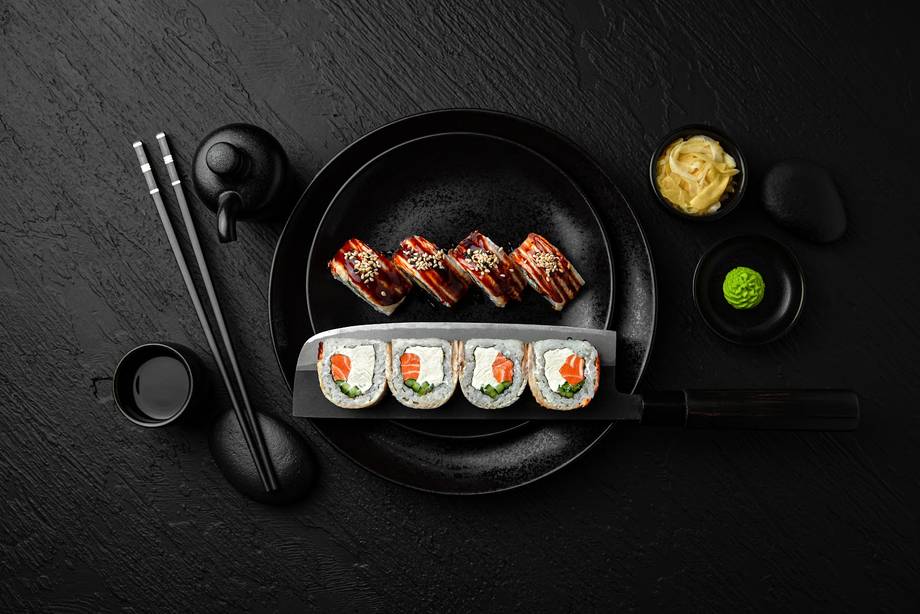 Assorted sushi rolls and nigiri arranged on black plate with wasabi and ginger