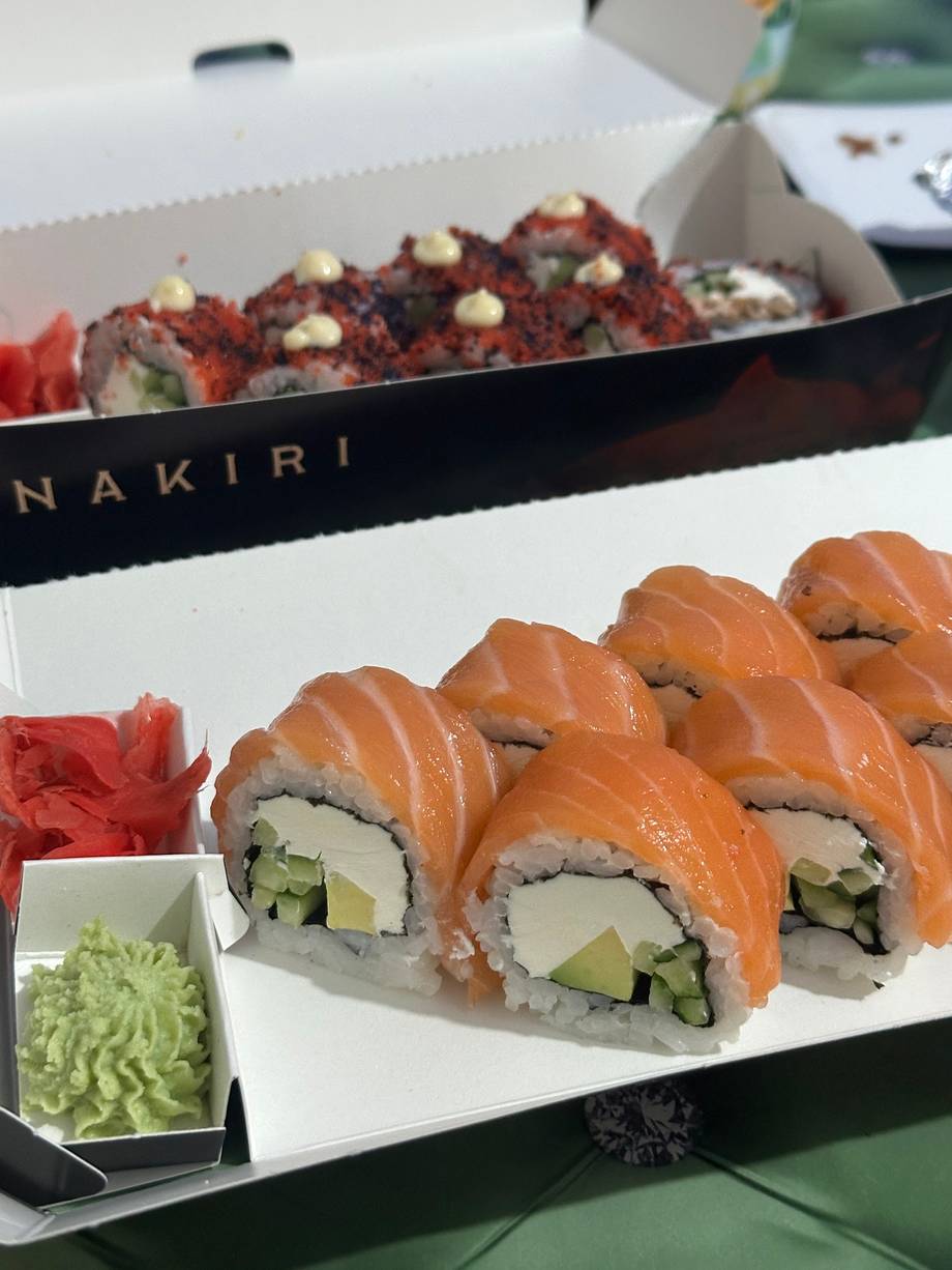 Salmon rolls and spicy tuna sushi on branded takeout trays