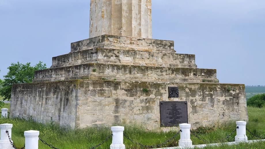 Historic stone monastery structure with tiered architecture and white fence markers