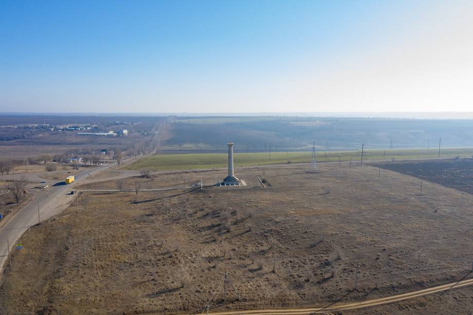Aerial view of open countryside with industrial structures and distant water body