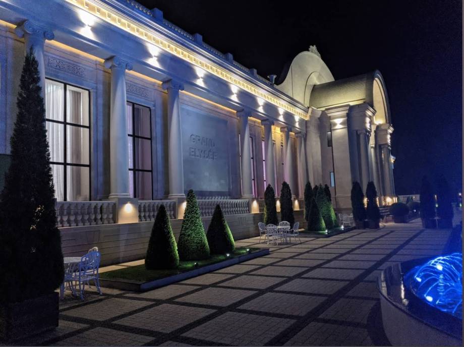 Elegant neoclassical facade illuminated at night with columned entrance and manicured landscaping