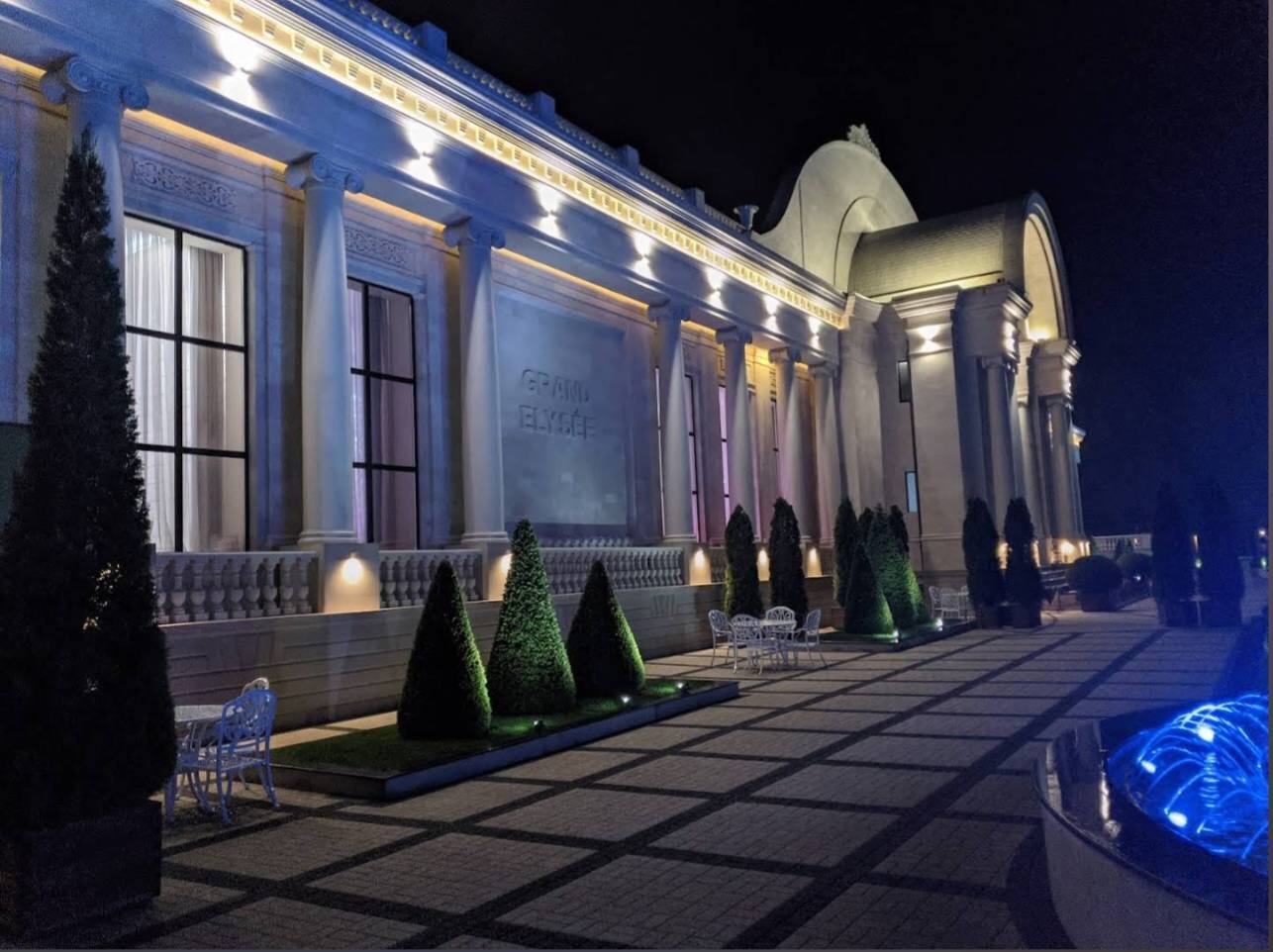 Elegant neoclassical facade illuminated at night with columned entrance and manicured landscaping