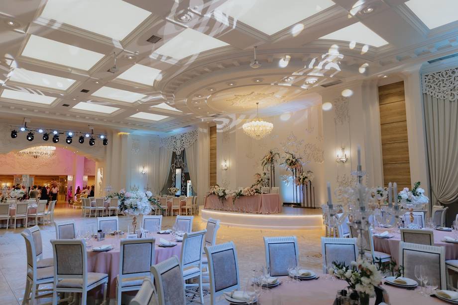 Elegant wedding reception hall with skylight ceiling, staged tables, and decorated stage area