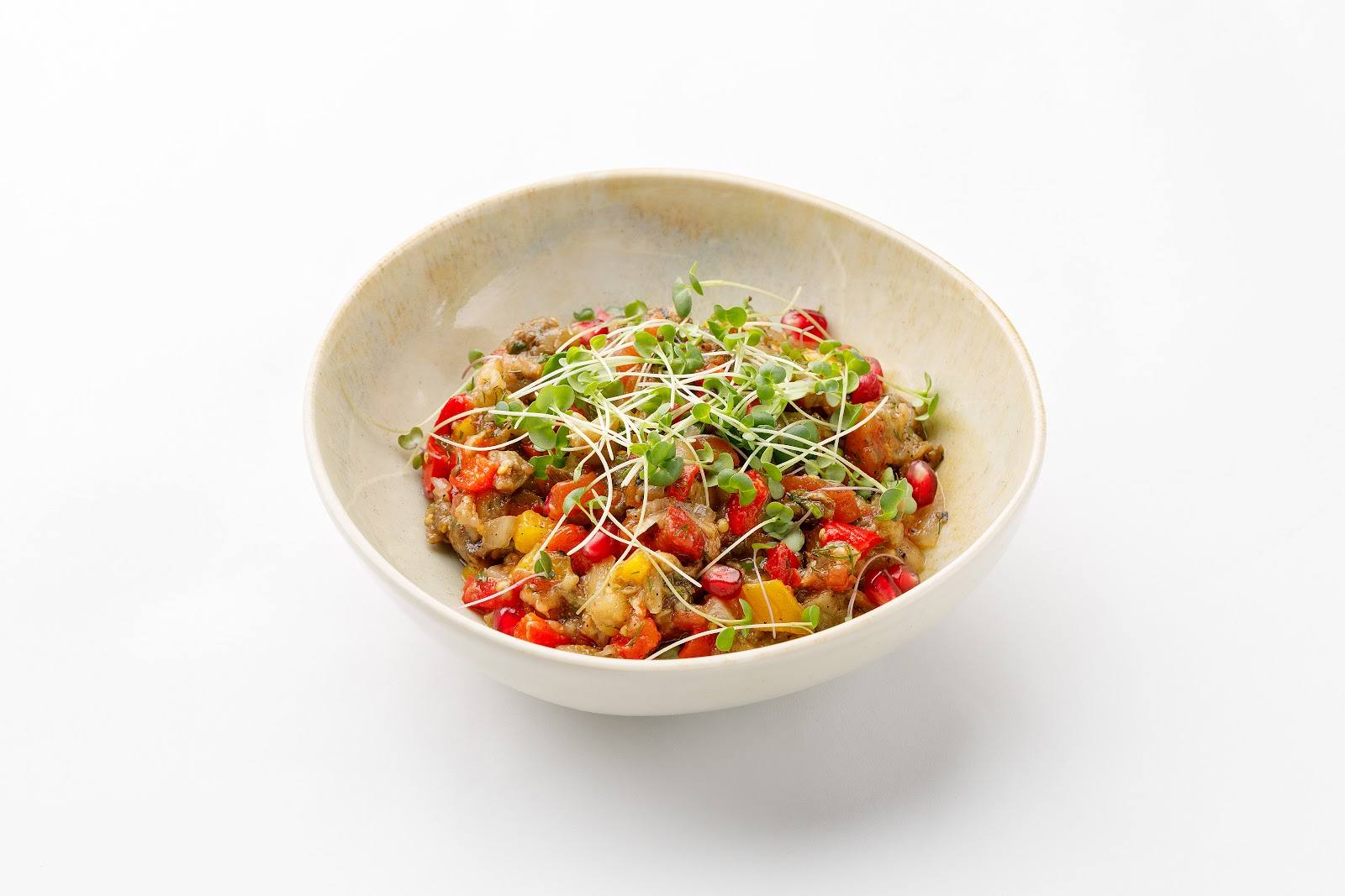 Colorful noodle dish with vegetables and protein in a white bowl
