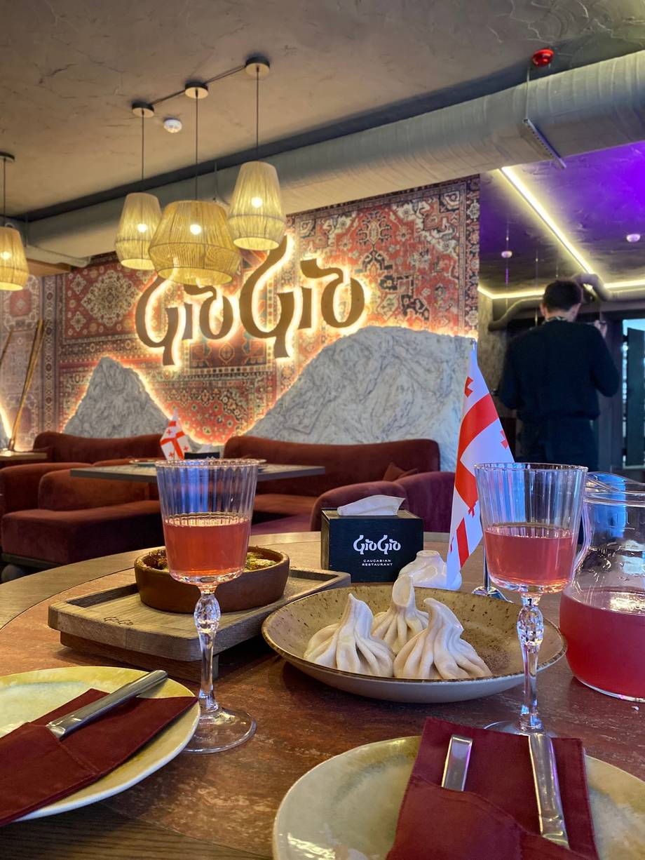 Elegant dining interior with neon signage, pendant lighting, and burgundy seating at GoGo restaurant
