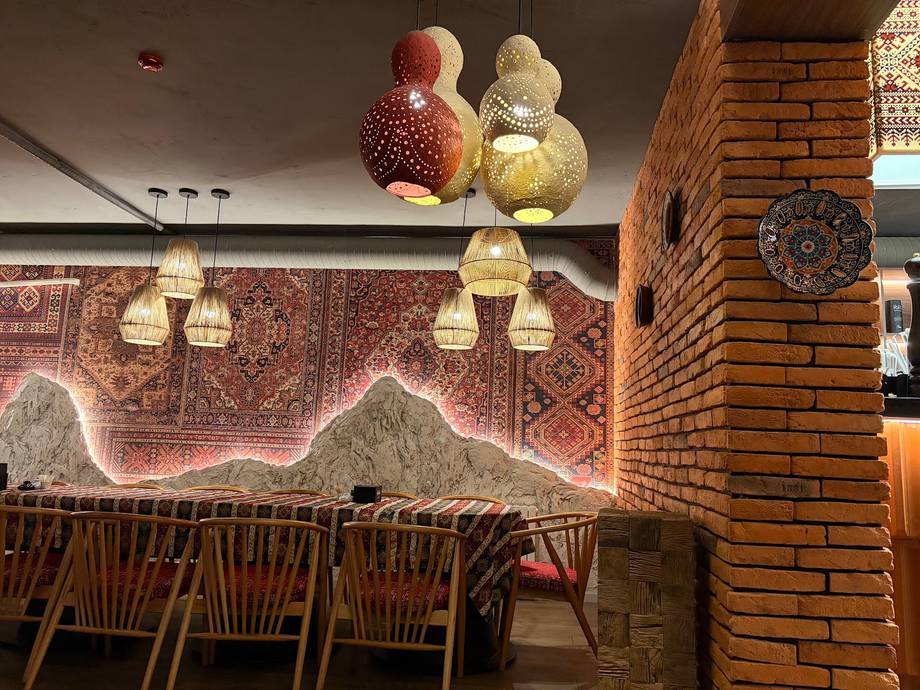 Modern restaurant interior with brick walls, contemporary pendant lighting, and decorative neon mountain artwork