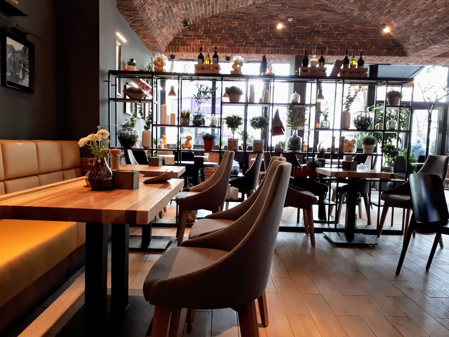 Modern restaurant interior with exposed brick ceiling, wooden tables, and contemporary seating