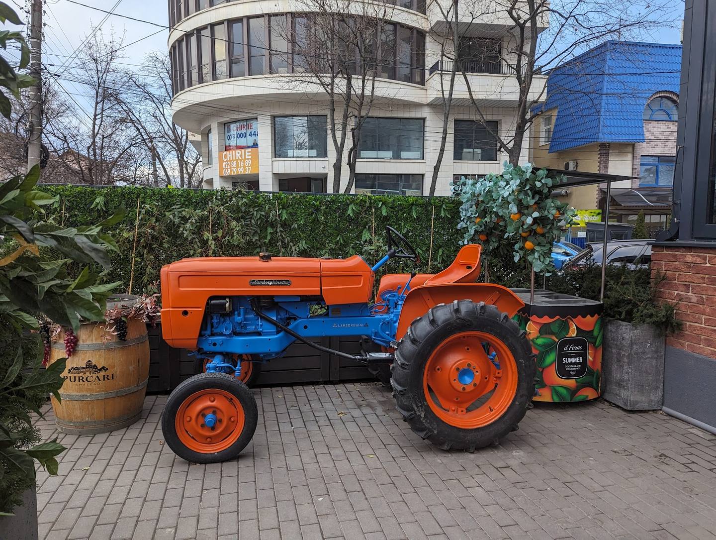 Vintage orange and blue tractor display in paved courtyard