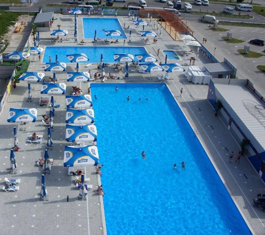 Aerial view of public outdoor swimming pool complex with multiple lanes and umbrellas