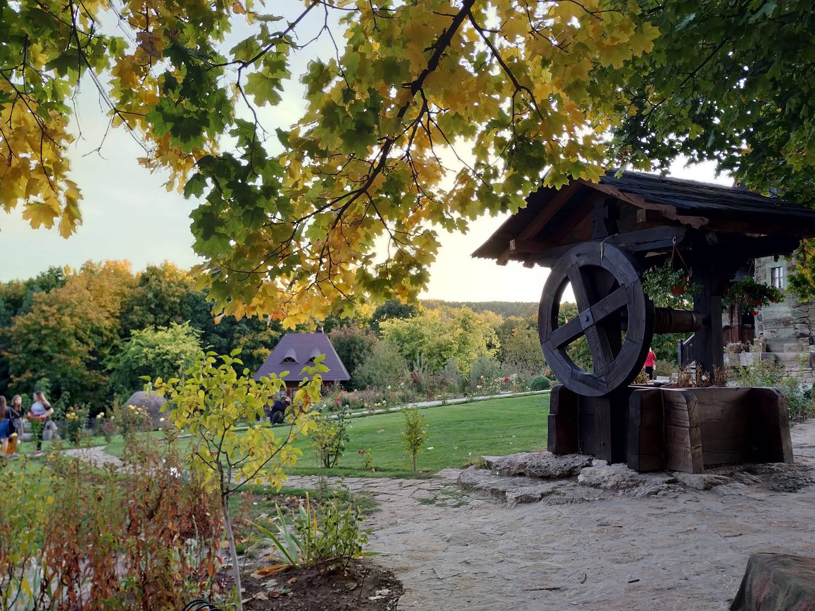 Large vintage water wheel installation in manicured garden setting with autumn foliage