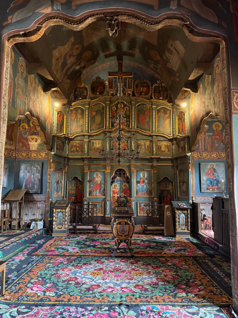 Orthodox monastery chapel interior with ornate wooden iconostasis and decorated vault ceiling