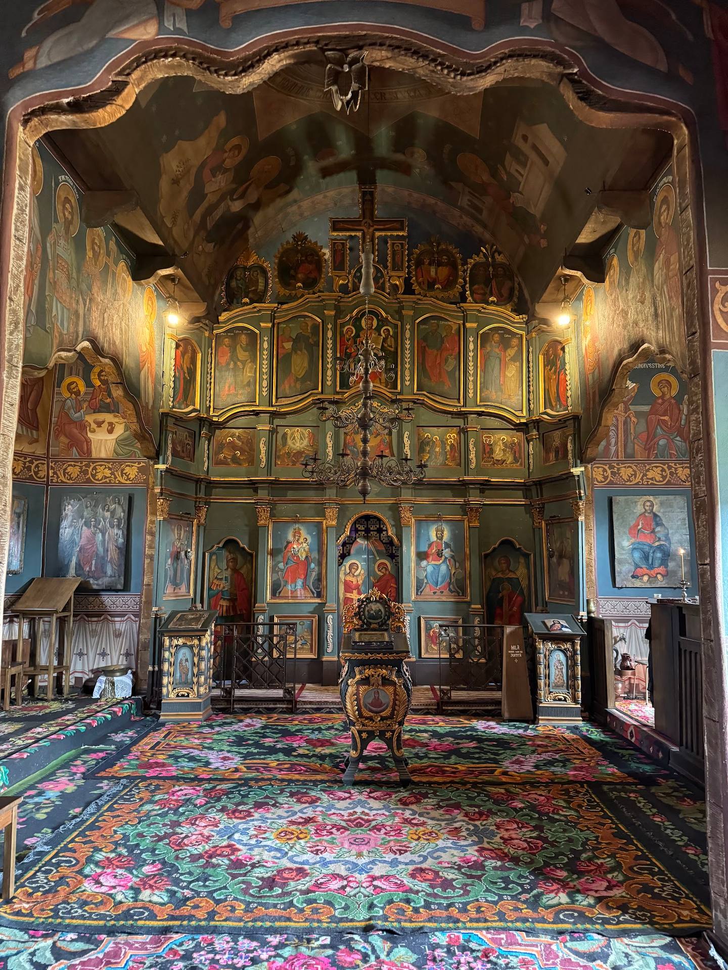 Orthodox monastery chapel interior with ornate wooden iconostasis and decorated vault ceiling