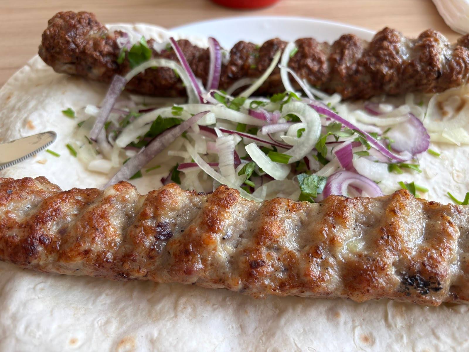 Grilled meat skewers with fresh onion and herb garnish