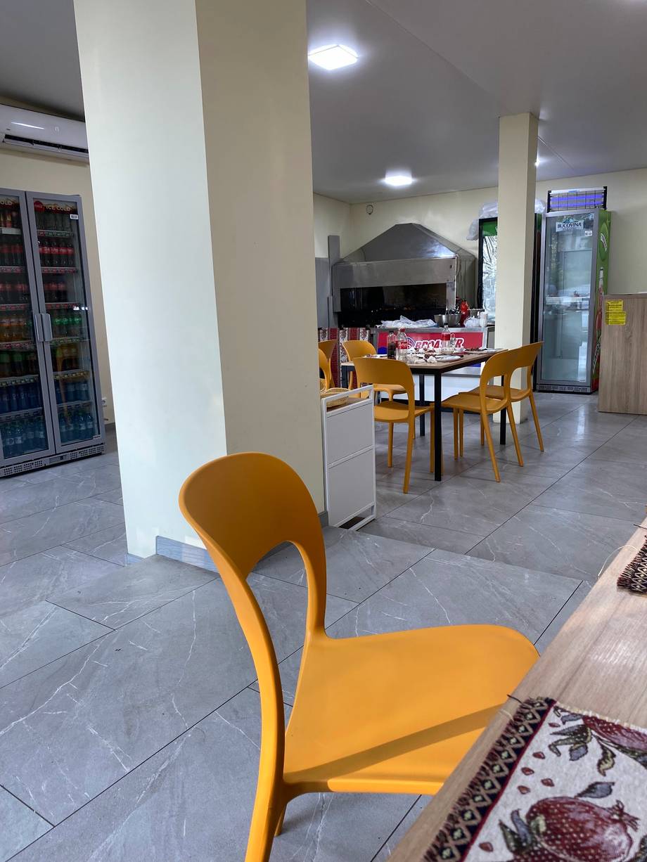 Modern casual dining space with yellow accent seating, refrigerated beverage displays, and mixed dining tables
