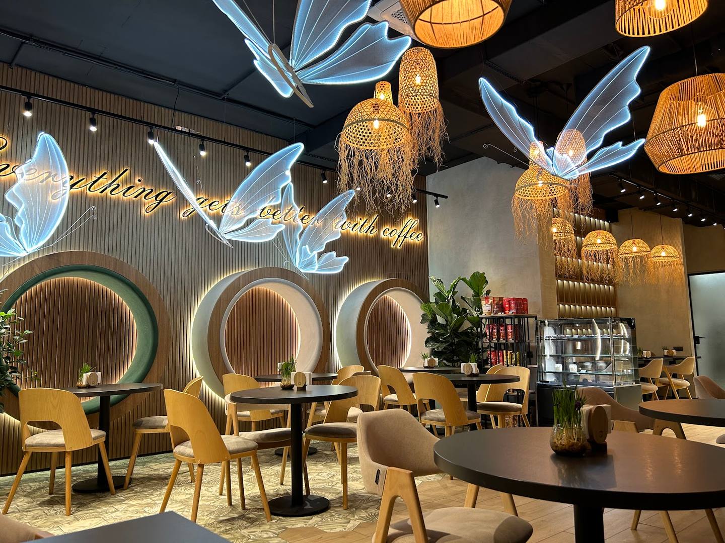 Modern café interior with sculptural angel wing chandeliers and neon circular wall art