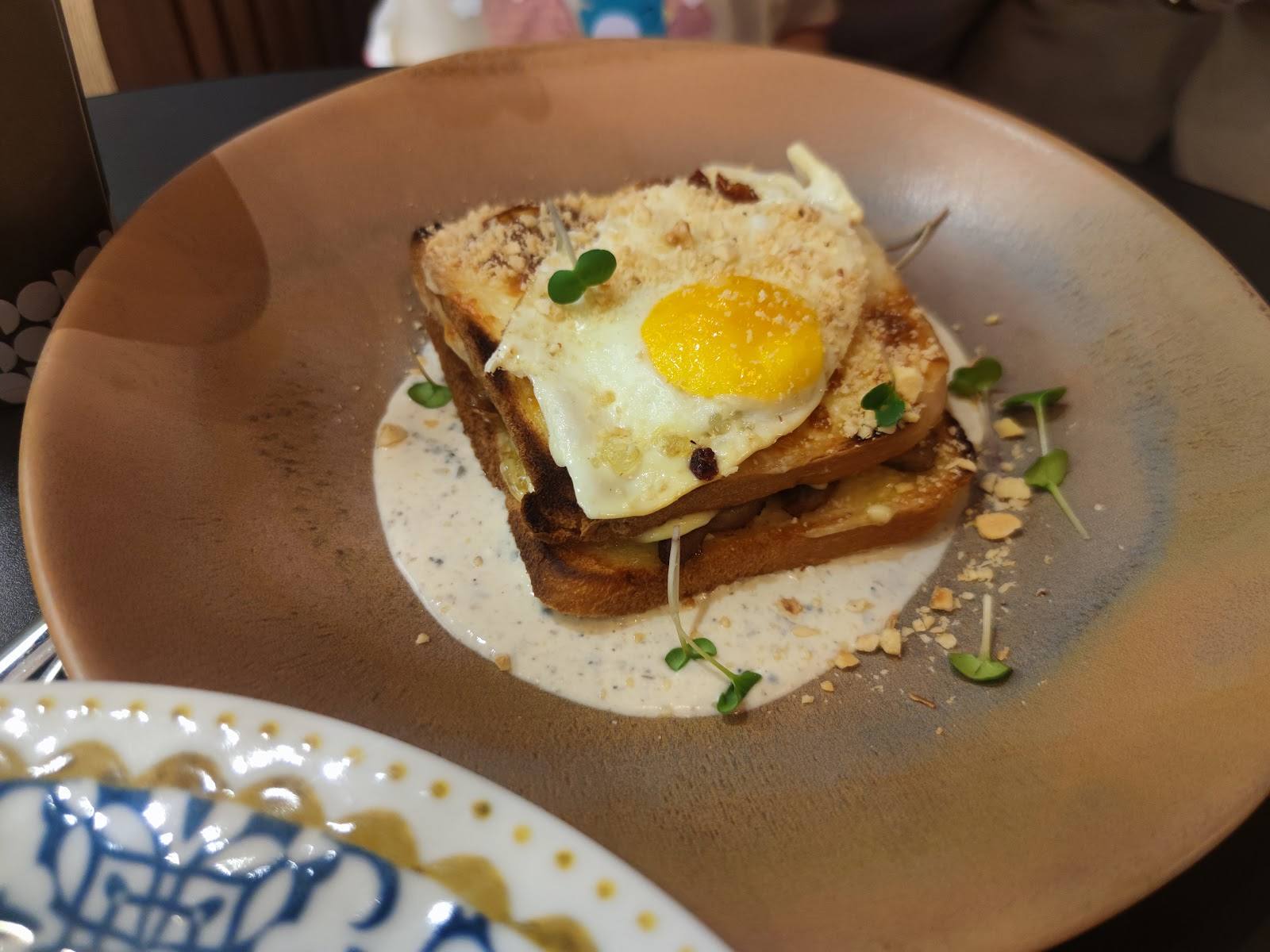 Egg and cheese toast on ceramic plate with microgreens garnish