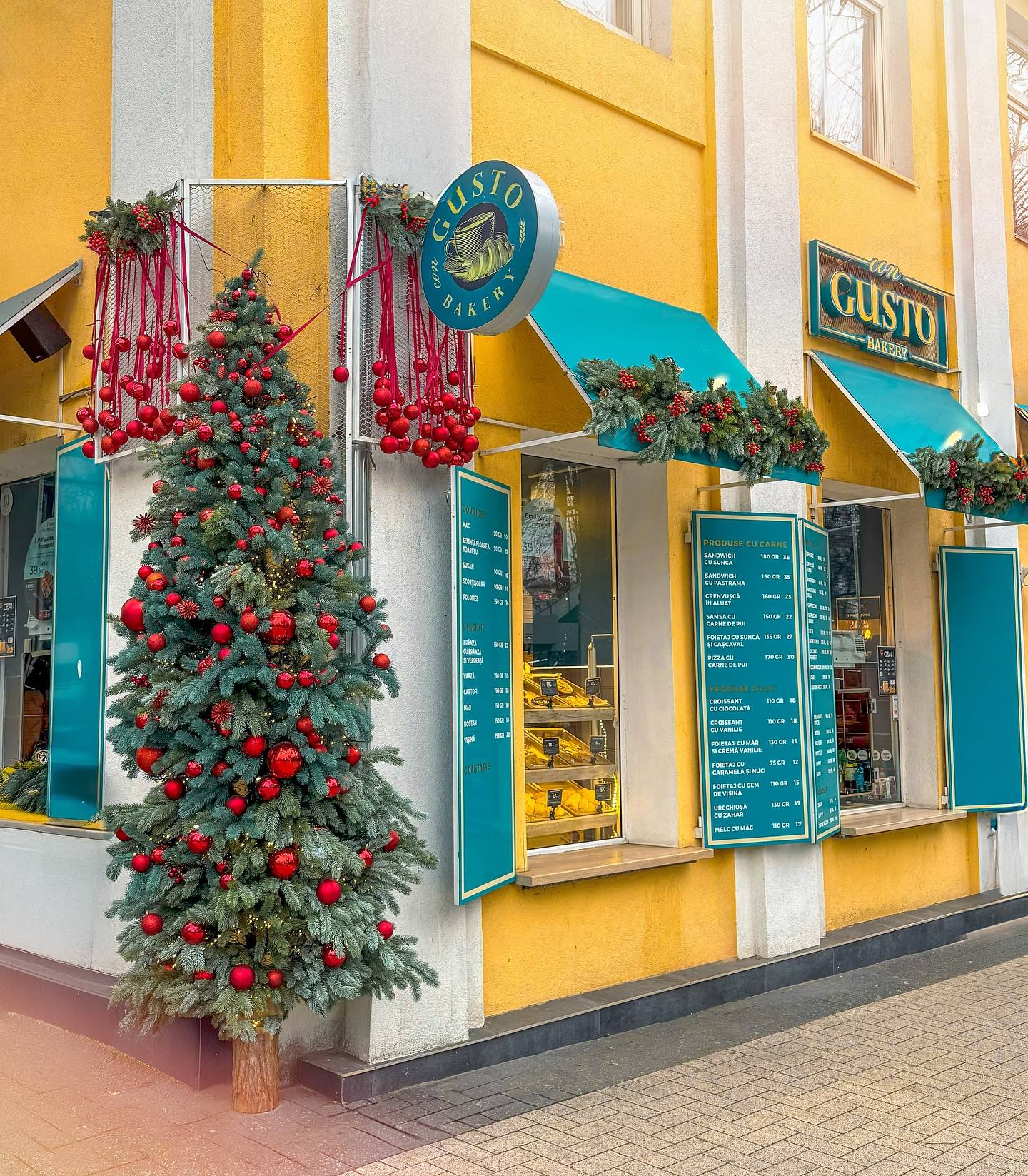 Charming cafe storefront with yellow and white striped facade, teal awnings, and vibrant red flowering vines