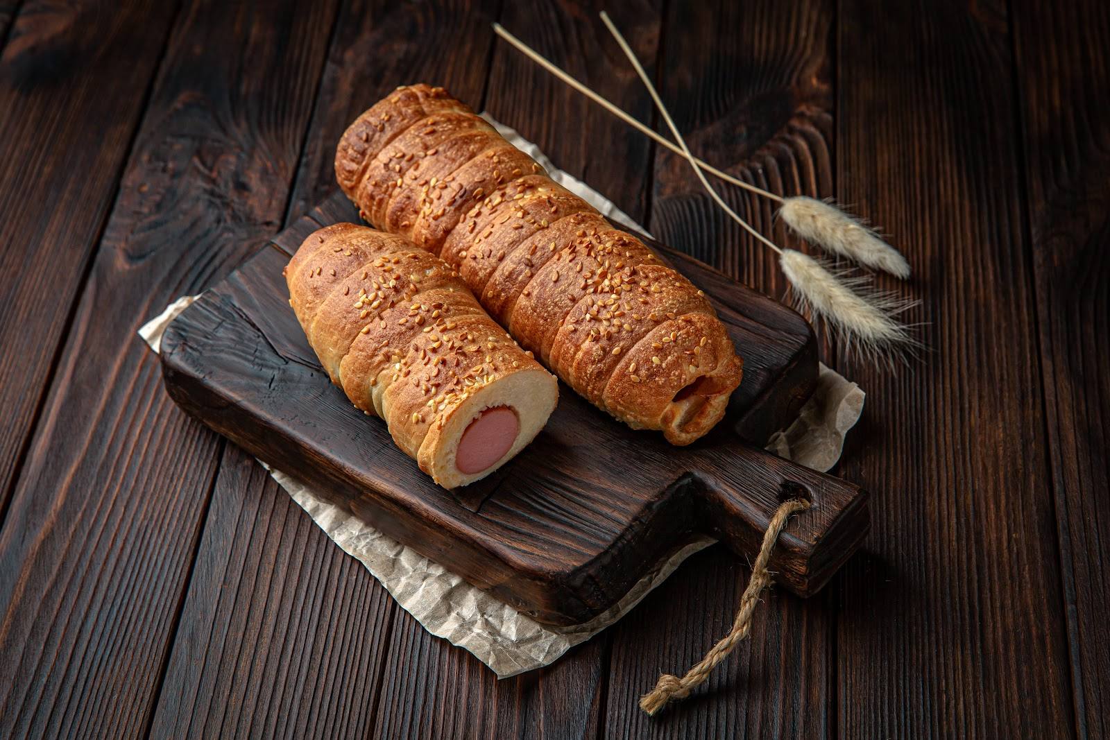 Artisanal smoked sausages on slate board with wheat garnish