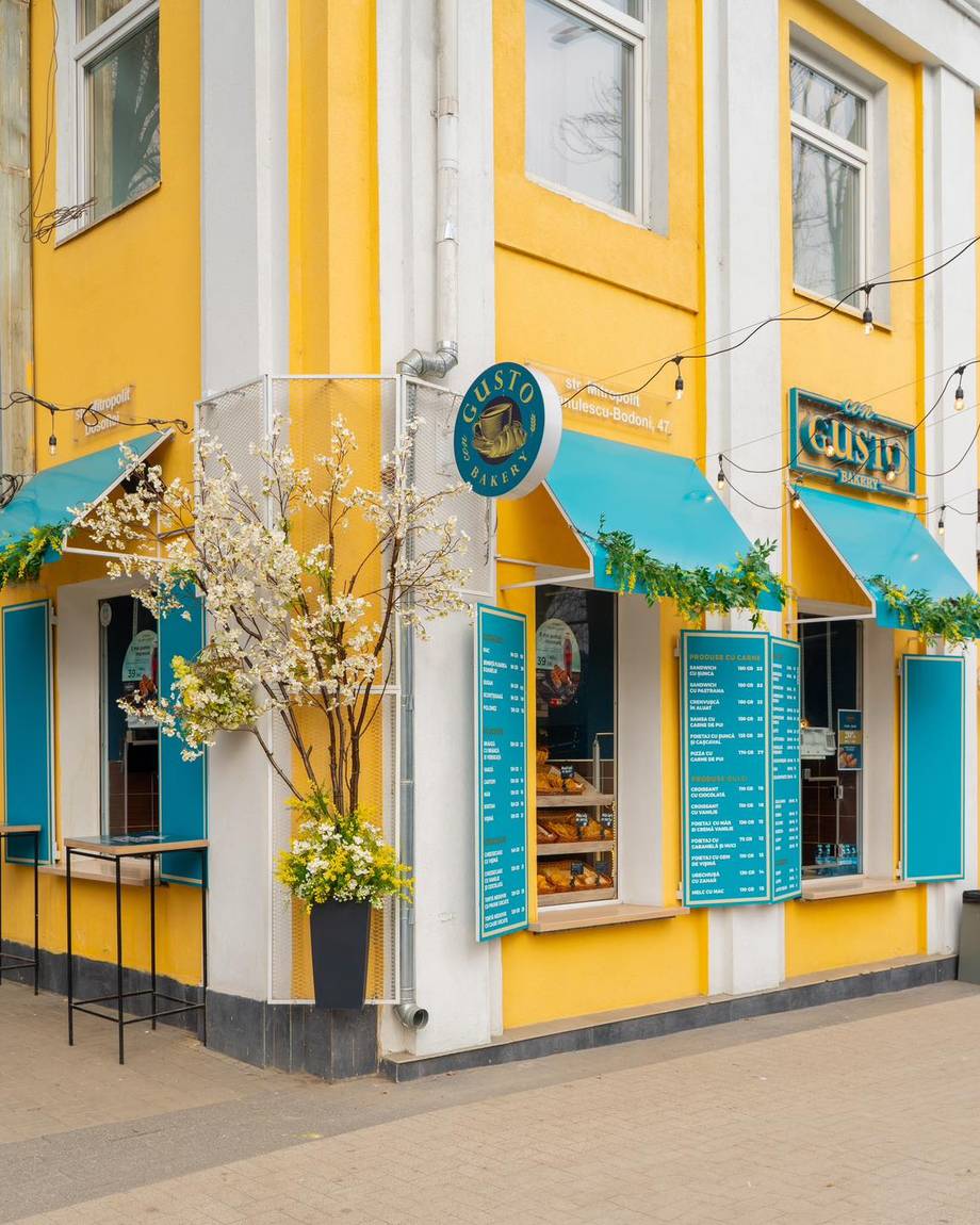 Bright yellow and blue corner storefront with turquoise awnings and signage, striking architectural character