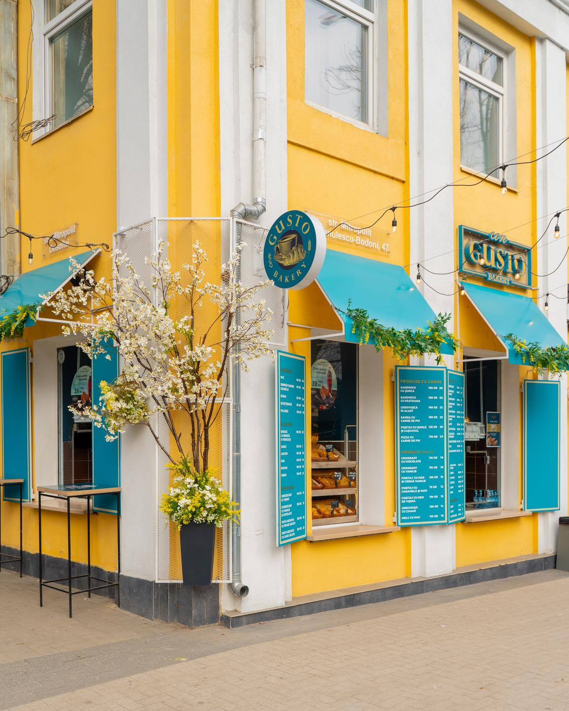 Bright yellow and blue corner storefront with turquoise awnings and signage, striking architectural character