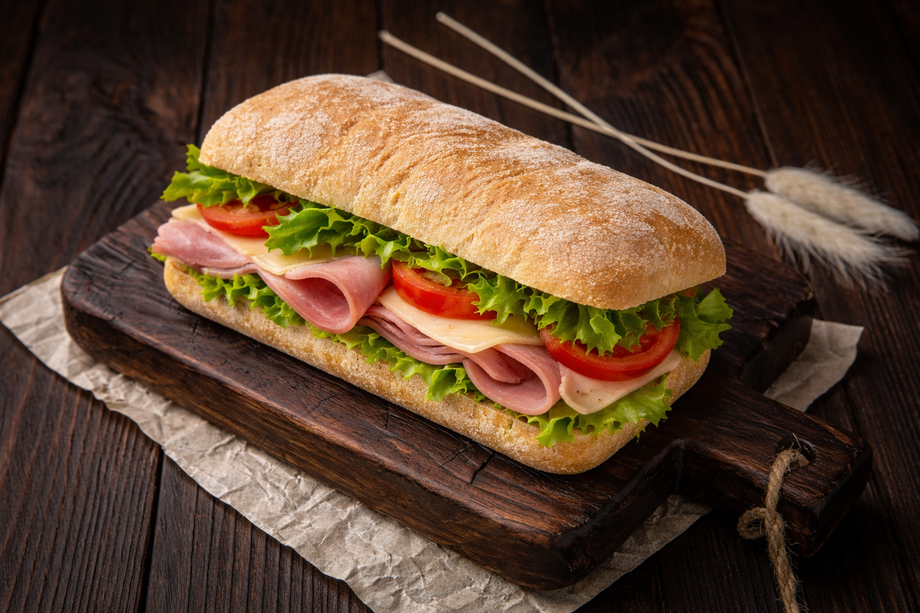 Gourmet ham and vegetable sandwich on rustic wooden board