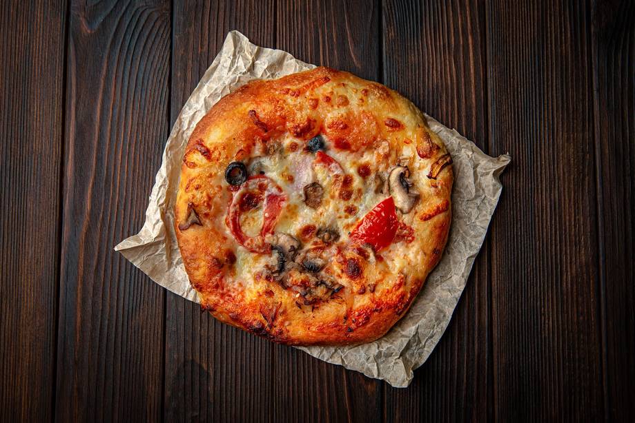 Wood-fired pizza with mixed toppings on parchment paper
