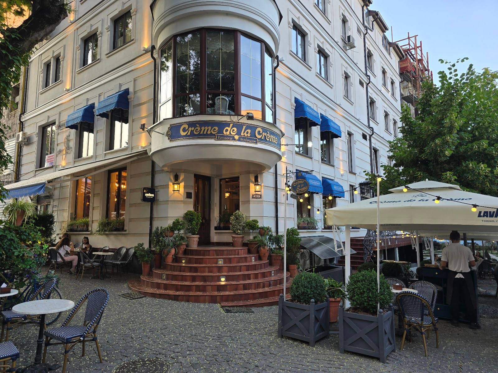 Elegant corner café with blue awnings and outdoor terrace seating