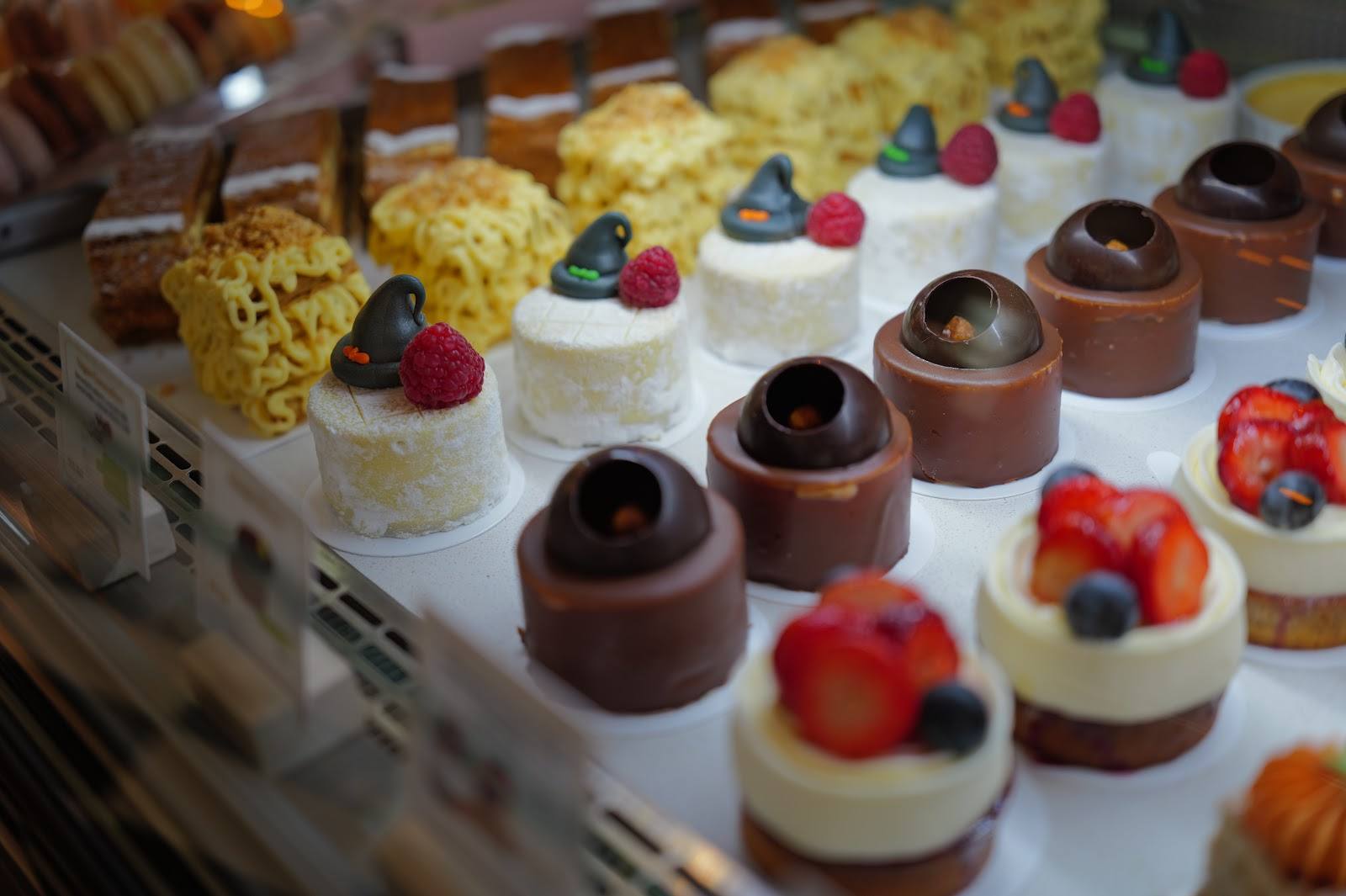 Assorted petit fours and mousse desserts with fresh berries displayed on pastry counter