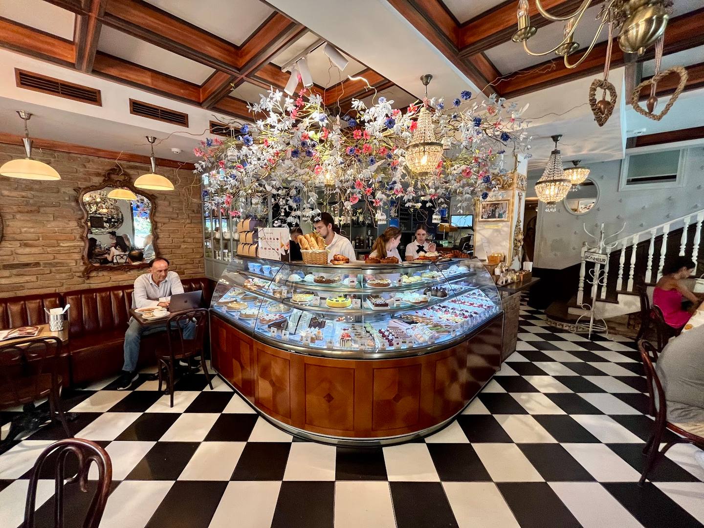 Elegant pastry shop with dramatic floral ceiling installation and curved display counter