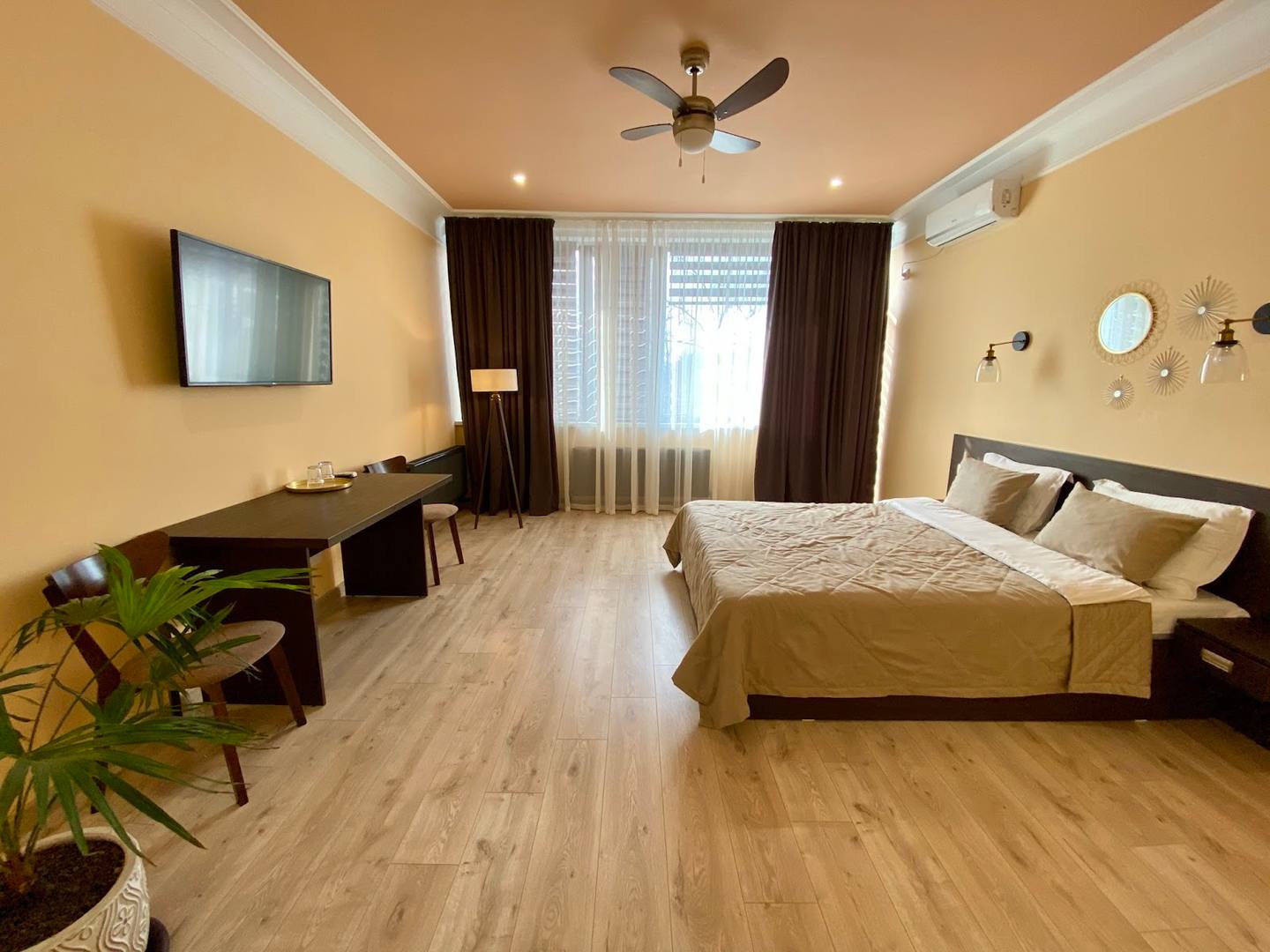 Spacious modern bedroom with queen bed, work area, and yellow accent walls