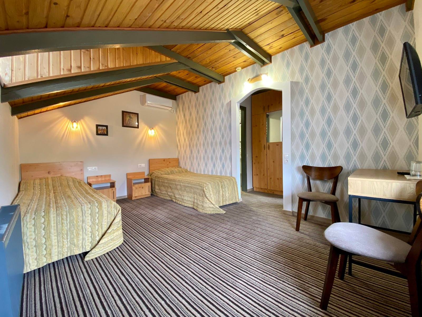 Spacious guesthouse room with exposed wooden beams and modern furnishings
